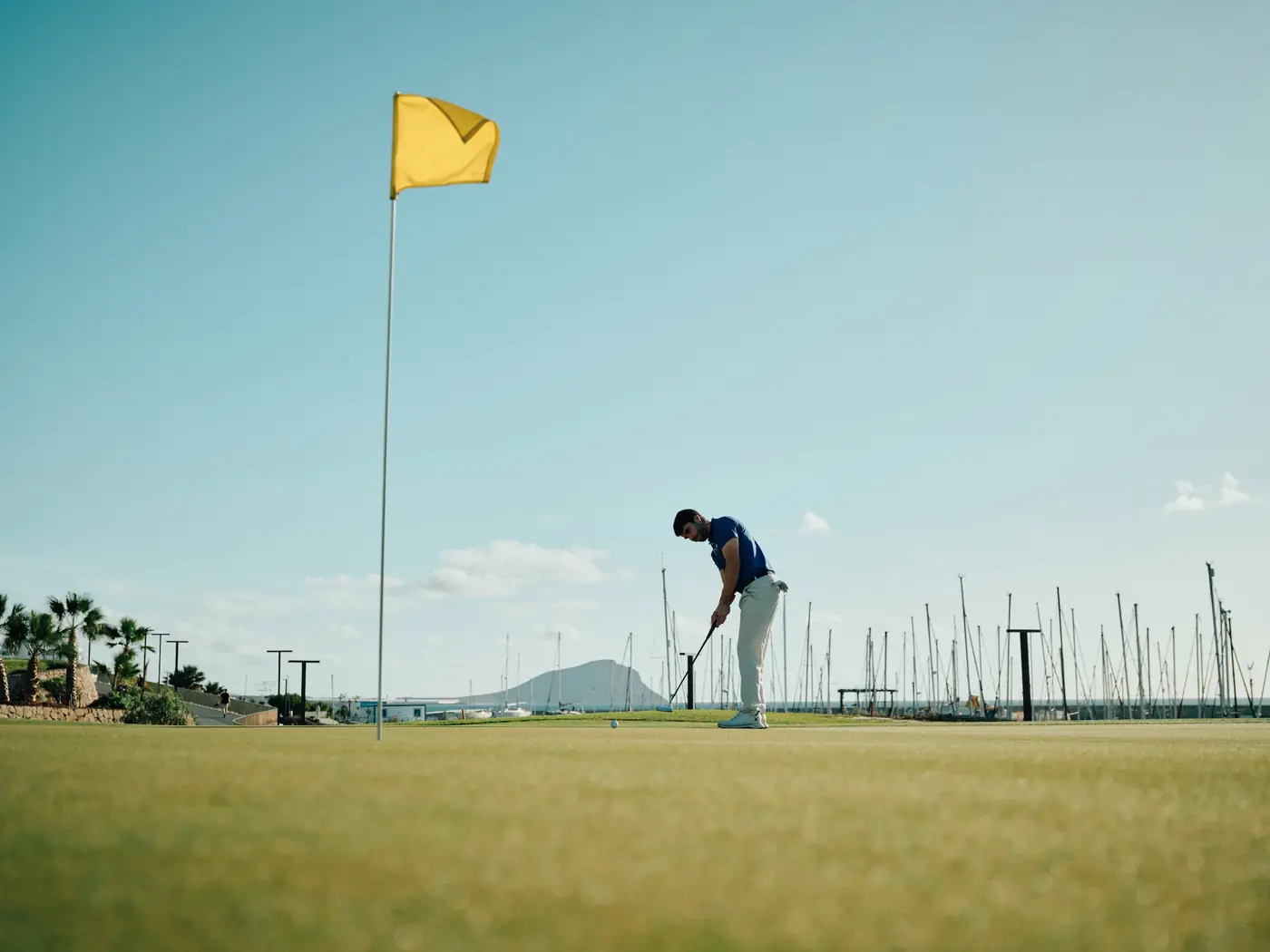 Golfer putting at Amarilla Golf with Tenerife's coastline behind
